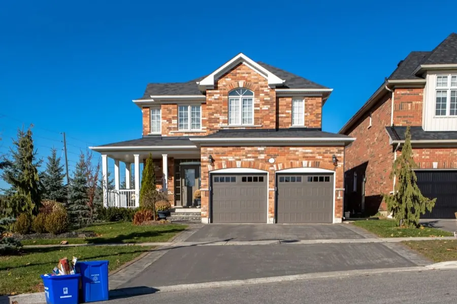 Two grey carriage garage doors with window inserts on a red-brick two-story home