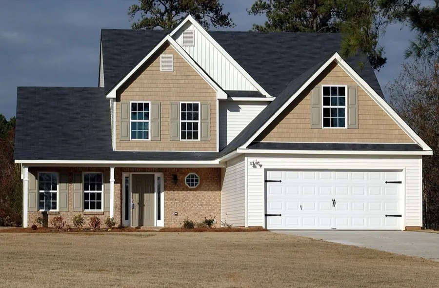 White carriage-style double garage door on a brick and shake-gable American home