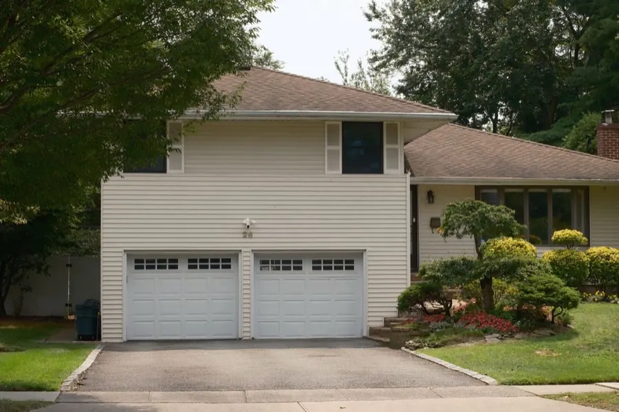 Two single raised-panel garage doors with window inserts on a split-level home